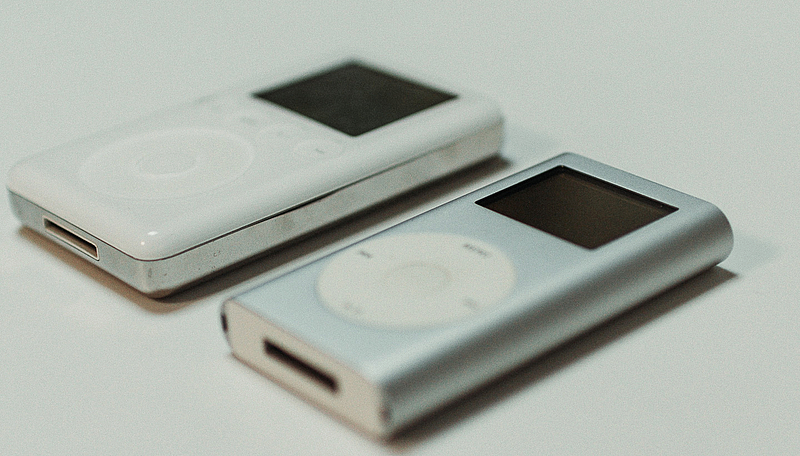 eine weißer iPod der 3. Generation und ein silberner iPod mini der 1. Generation liegen auf einem weißen Untergrund
