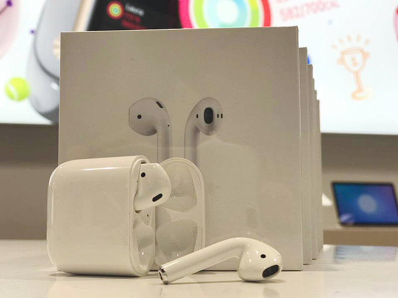 weiße Verpackung von AirPods und ausgepackte AirPods liegen auf einem weißen Tisch 