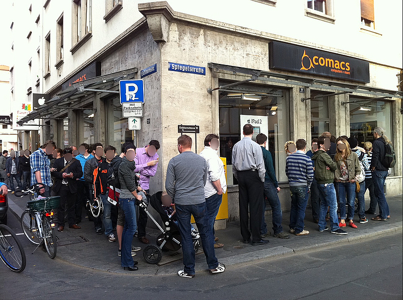 Viele Menschen stehen vor dem Geschäft an und warten auf Einlass.